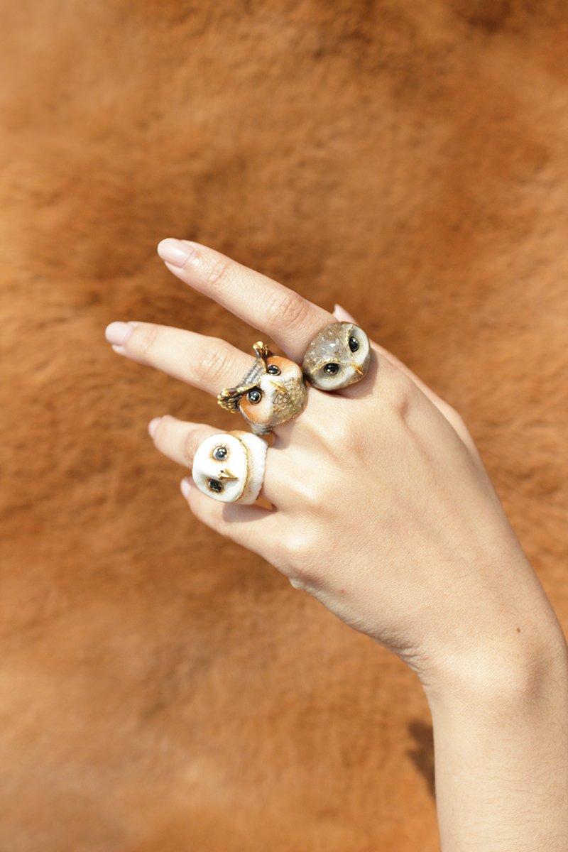 Close-up of unique owl rings on a hand, showcasing intricate details and playful design.