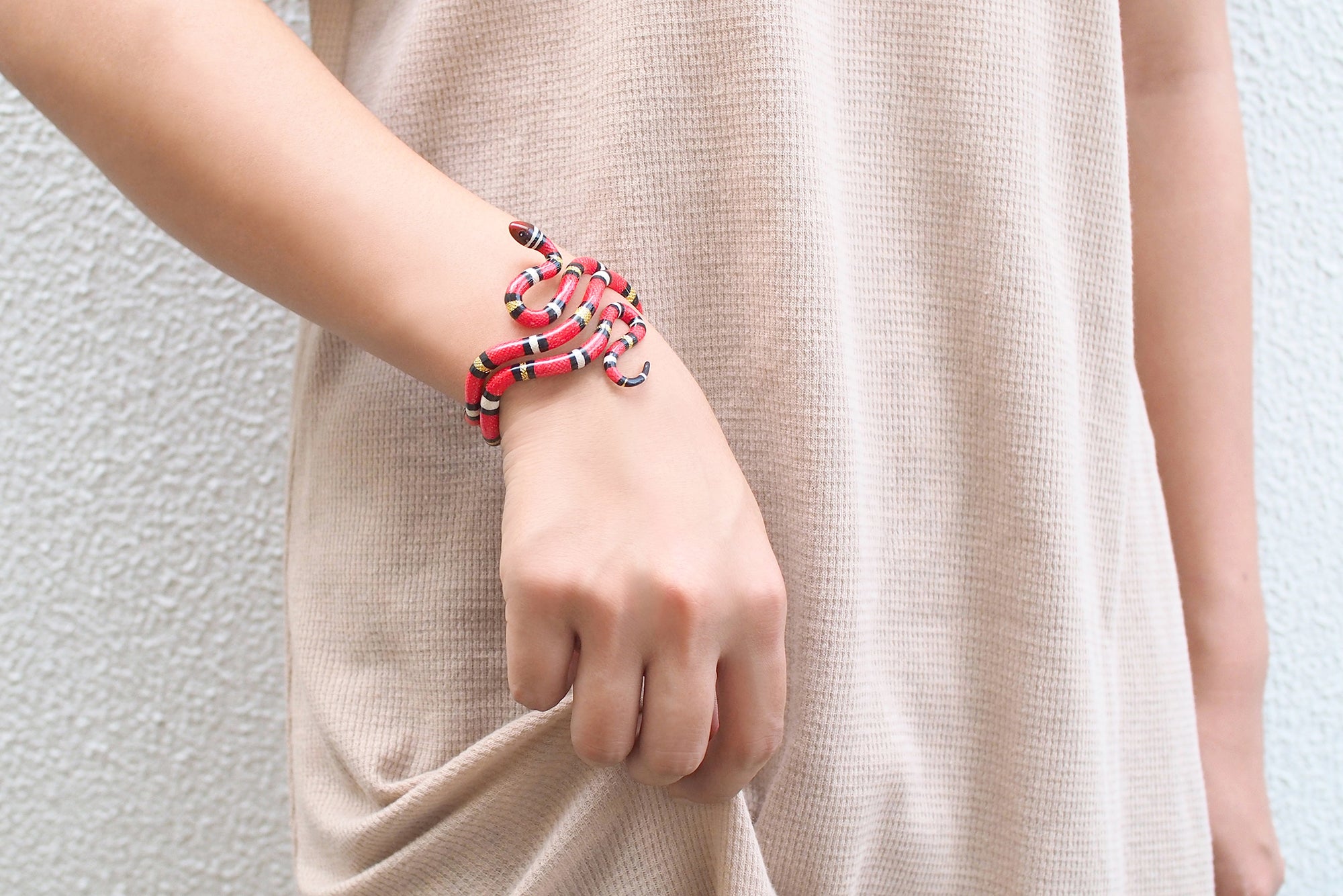 A striking red snake bangle elegantly around a model's wrist.