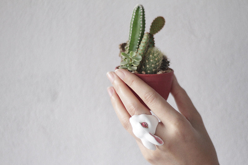 Close-up of a hand wearing a rabbit ring while holding a small cactus pot.