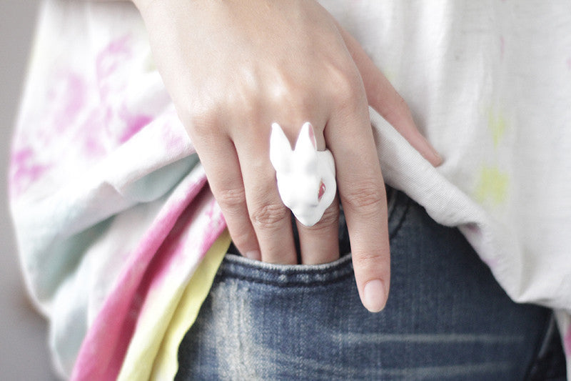 A playful white bunny ring worn on a hand on a casual outfit.