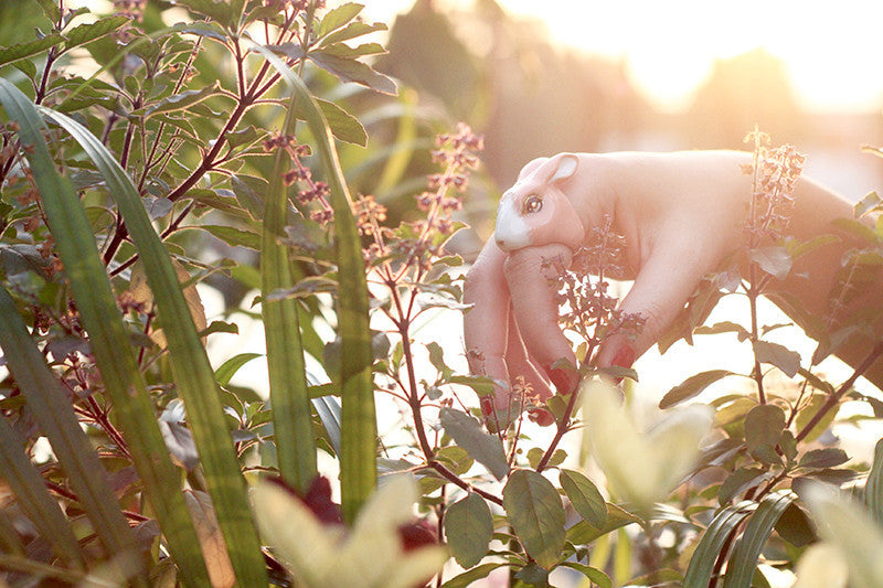 A hand wearing an adorable rabbit ring in. a nature setting.