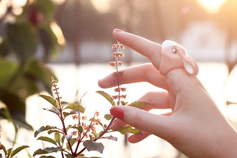 A hand wearing an adorable rabbit ring in. a nature setting.