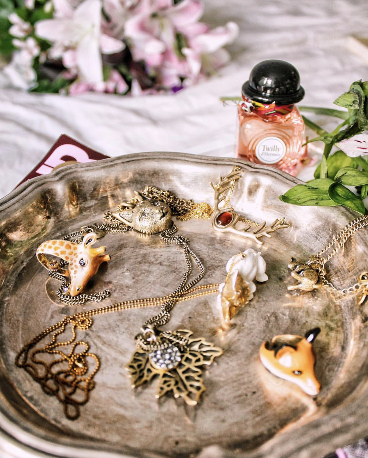 A collection of whimsical animal-themed jewelry on a silver tray.