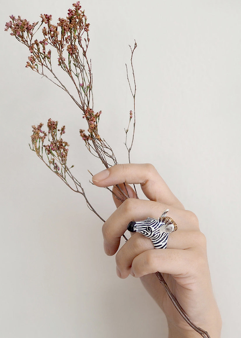 Close-up of a zebra ring worn on a hand holding dried flowers.