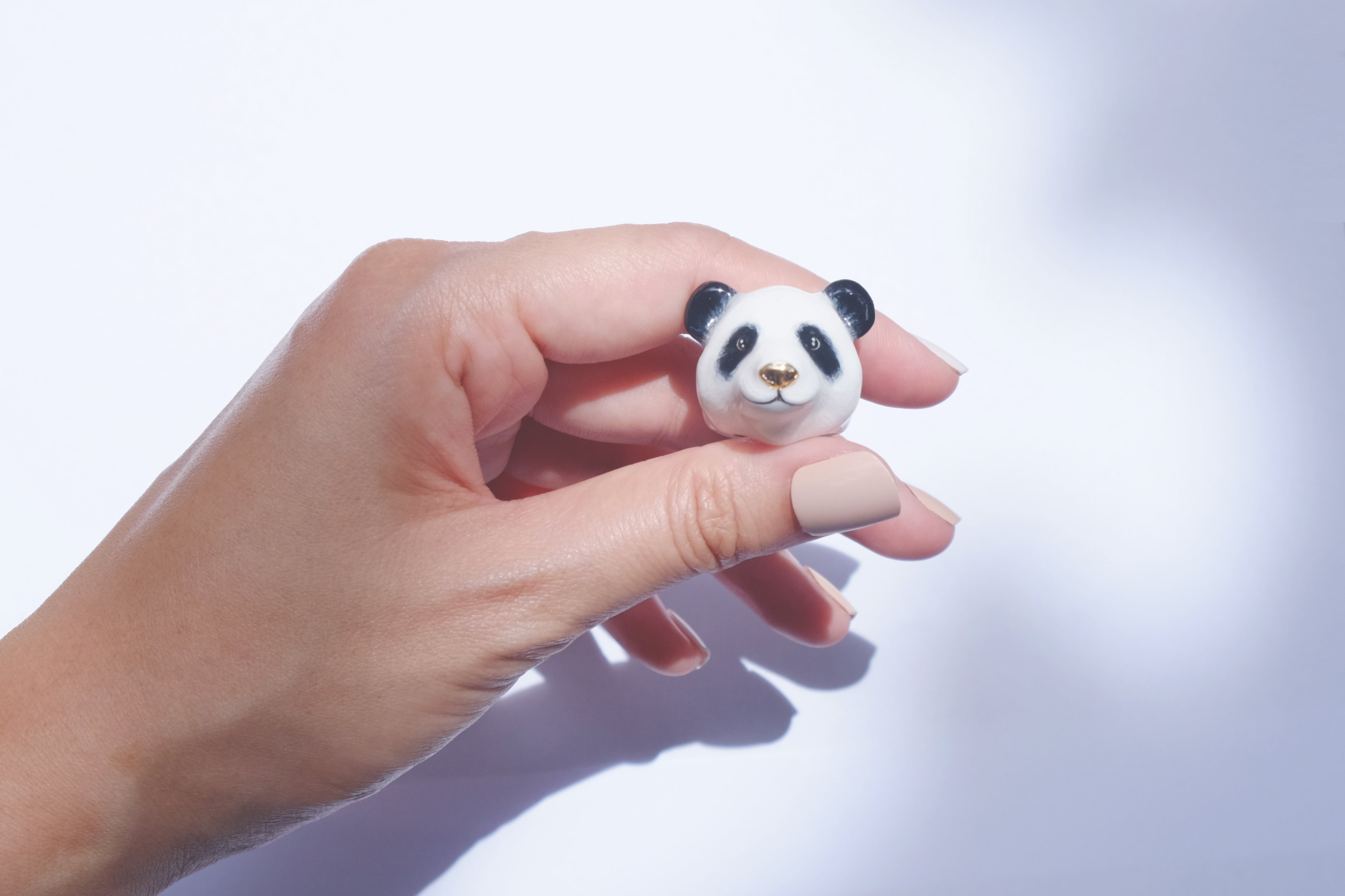 Close up of a hand holding an adorable panda ring in black and white design.