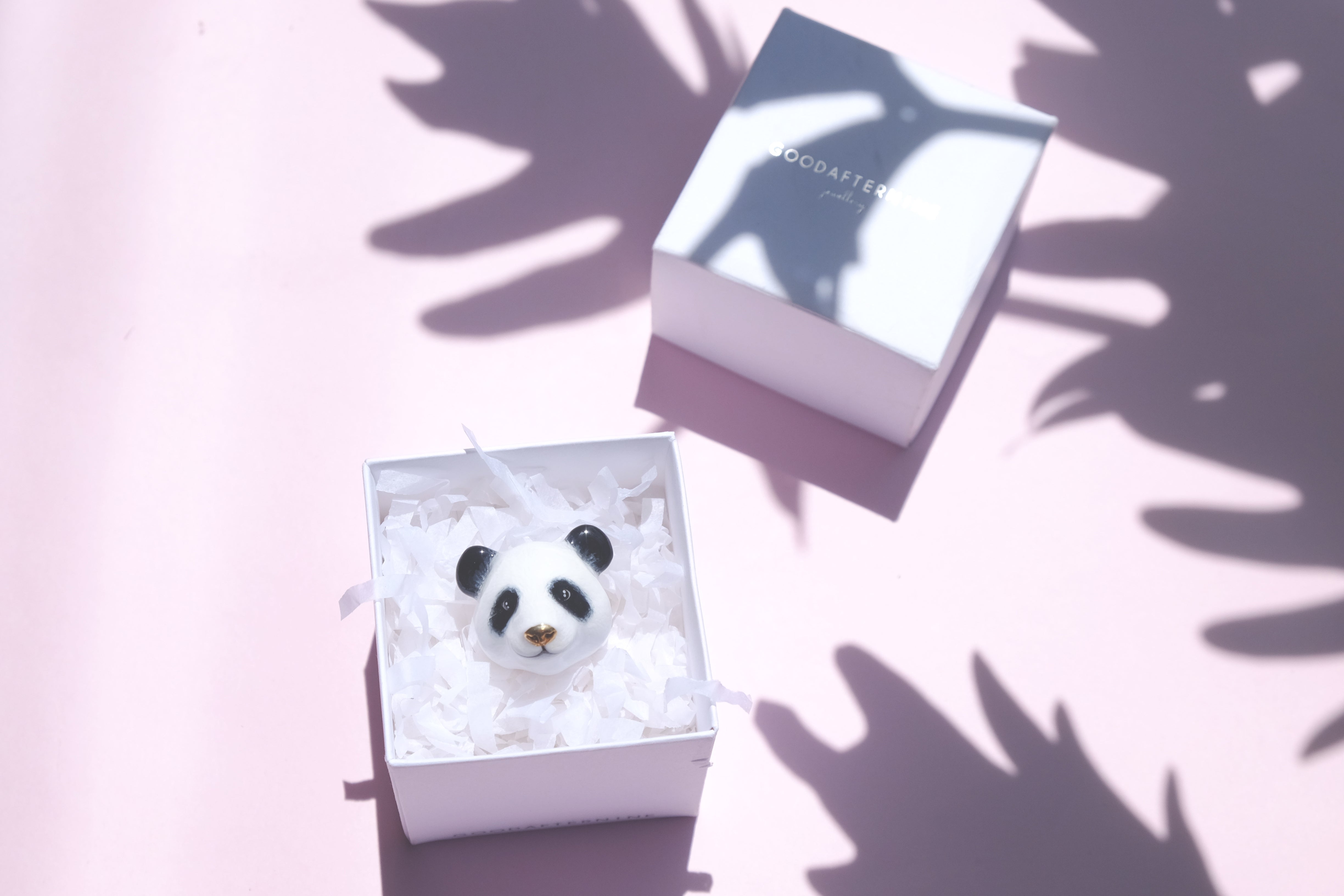 An adorable panda ring in a box against a soft pink background.