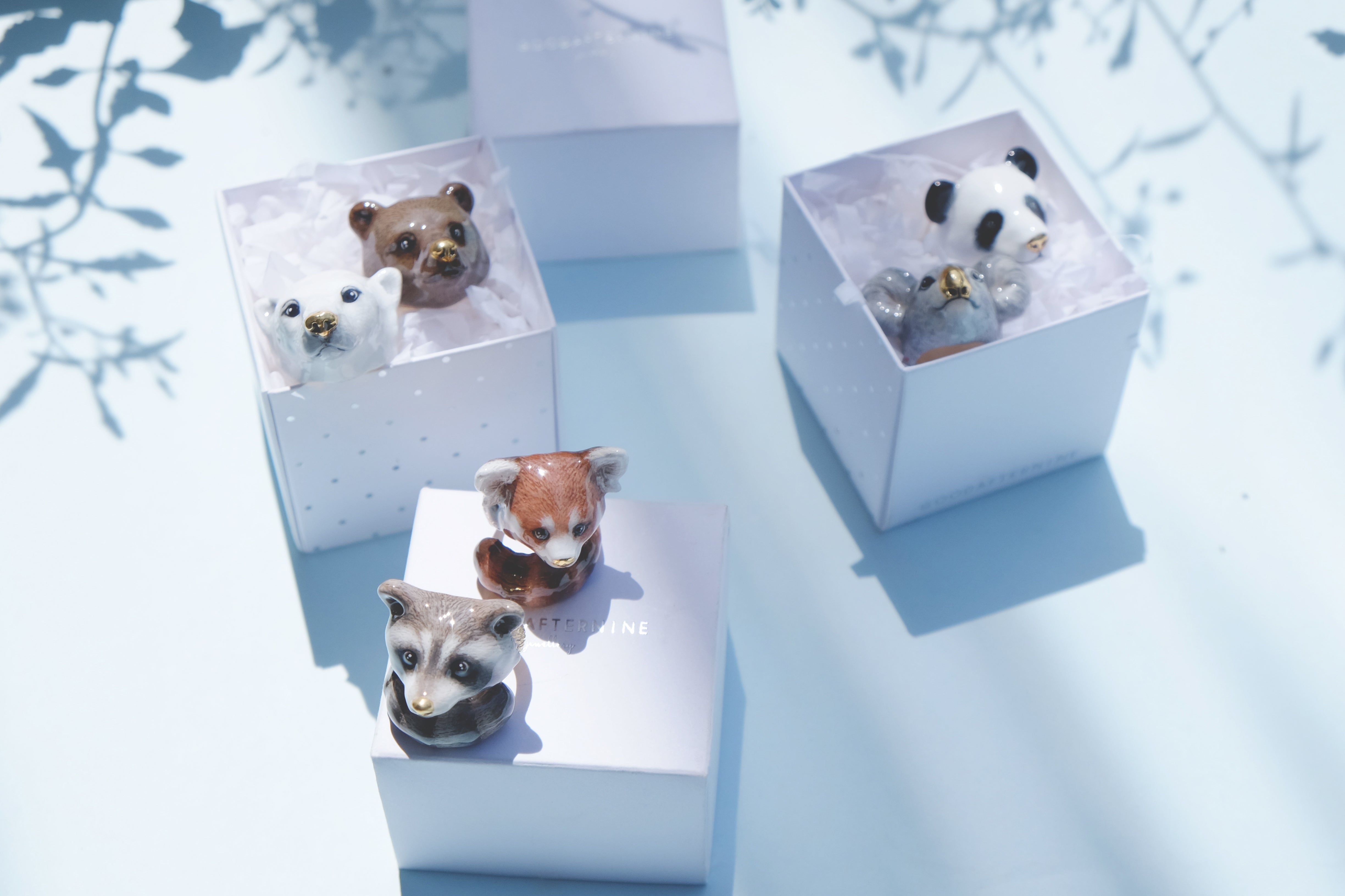 Six cute animal rings in boxes: a panda, koala, polar bear, grizzly bear, raccoon, and red panda against a soft blue background.