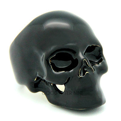 A shiny black skull ring with hollow eye sockets and detailed features.