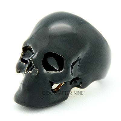 A shiny black skull ring with hollow eye sockets and detailed features.