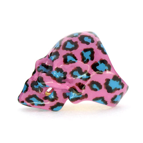 Playful skull ring featuring a pink base with a leopard pattern in black and blue, perfect for unique jewelry lovers.
