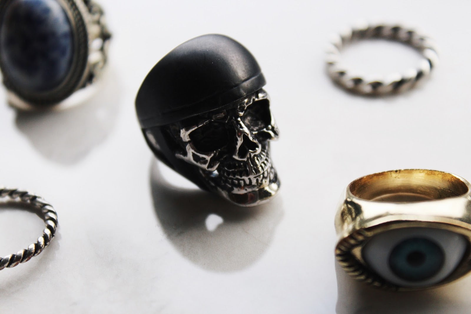 A detailed ring featuring a skull with helmet design placed on a white background with other unique rings.