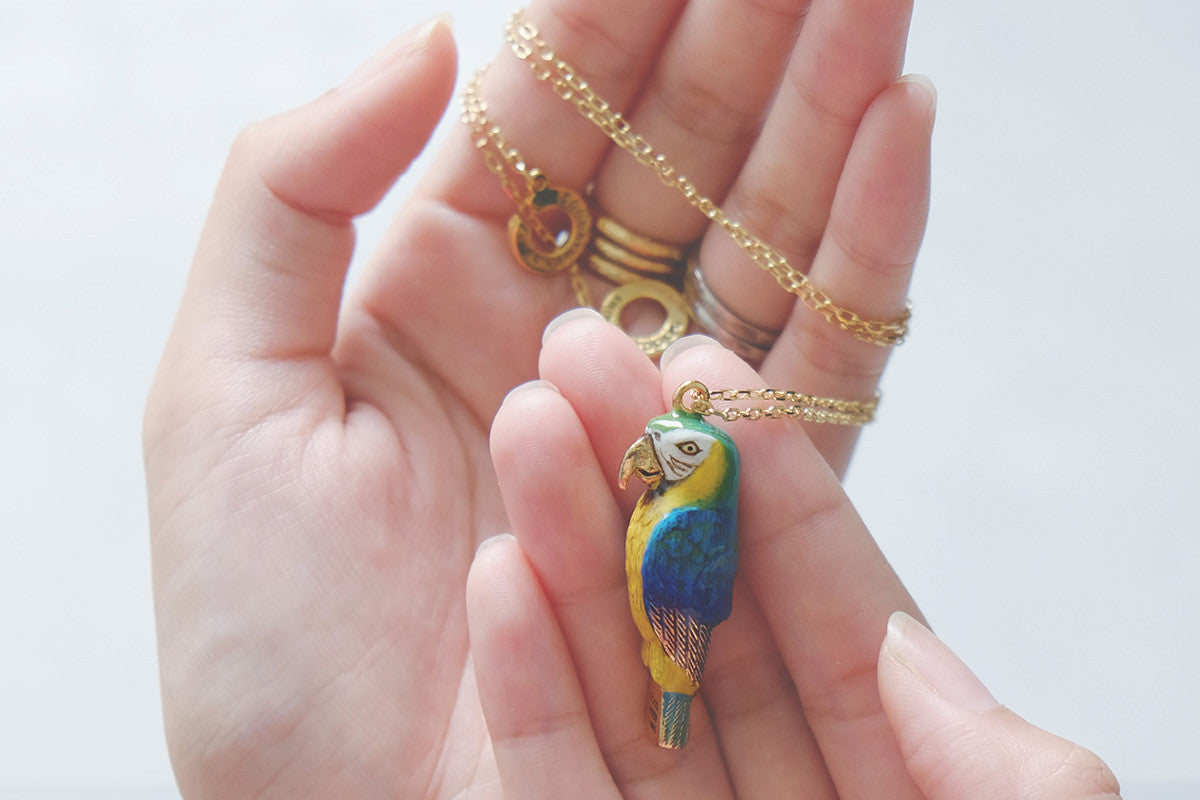 A vibrant blue macaw whistle necklace held in a hand.