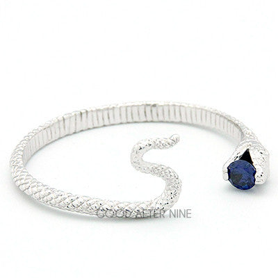 Unique silver snake bangle with a blue gemstone at its mouth.