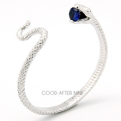 Stunning silver snake bangle with a blue gemstone at its mouth.