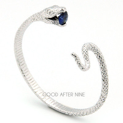 A silver bangle designed in the shape of a snake, featuring intricate details and a blue gemstone set at the mouth.