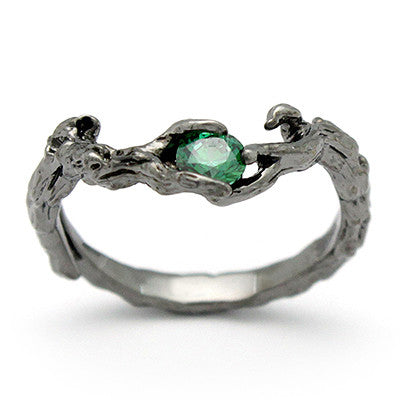 A unique ring designed to resemble natural wood, featuring a central green gemstone.