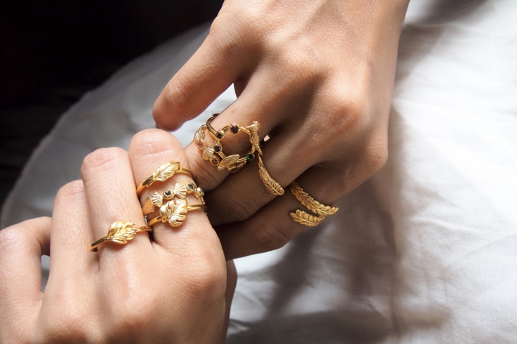 A charming collection of gold rings worn on fingers, featuring animal and leaf designs.