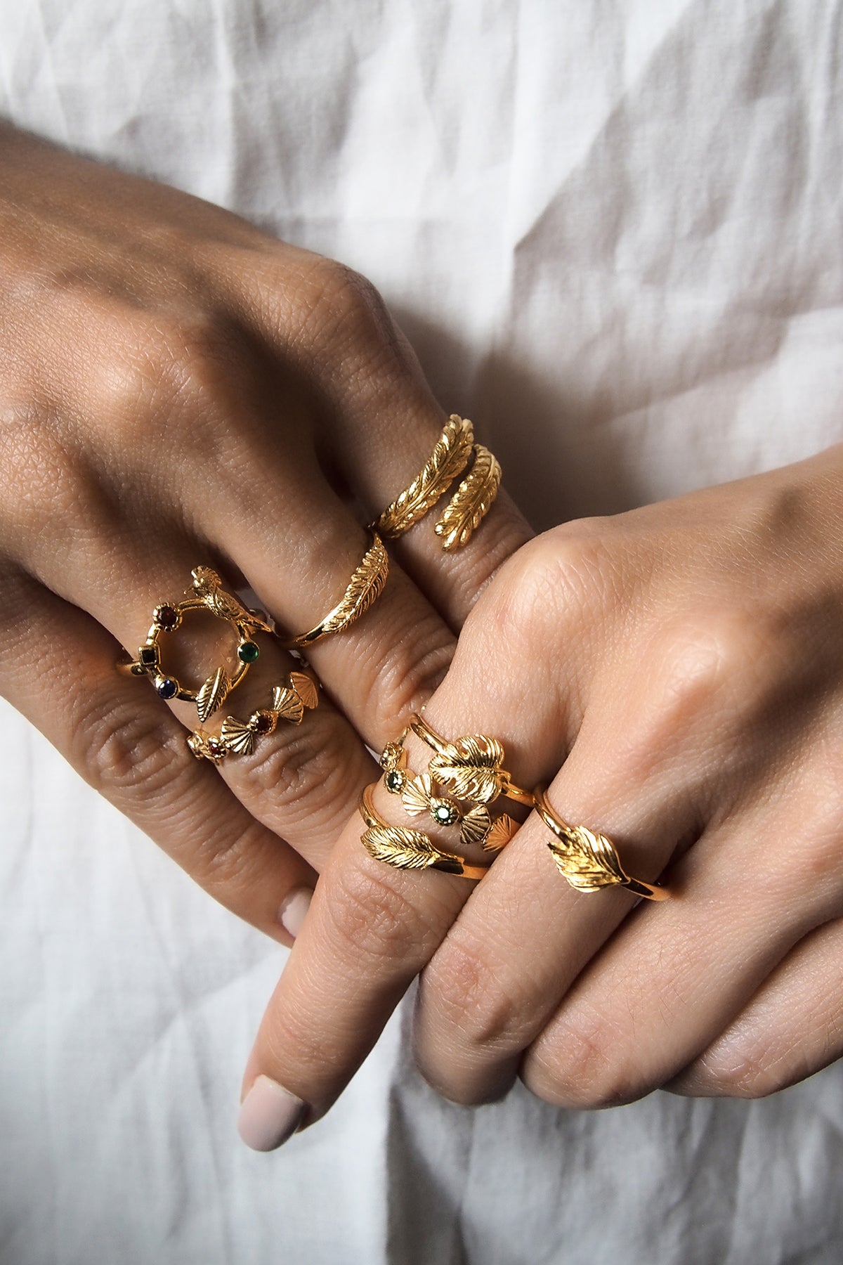 A collection of gold rings featuring animal and leaf motifs worn on fingers.