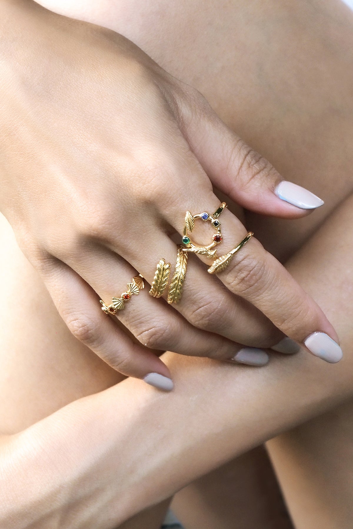 A collection of stylish gold rings featured animal and leaf motif design worn on a hand.