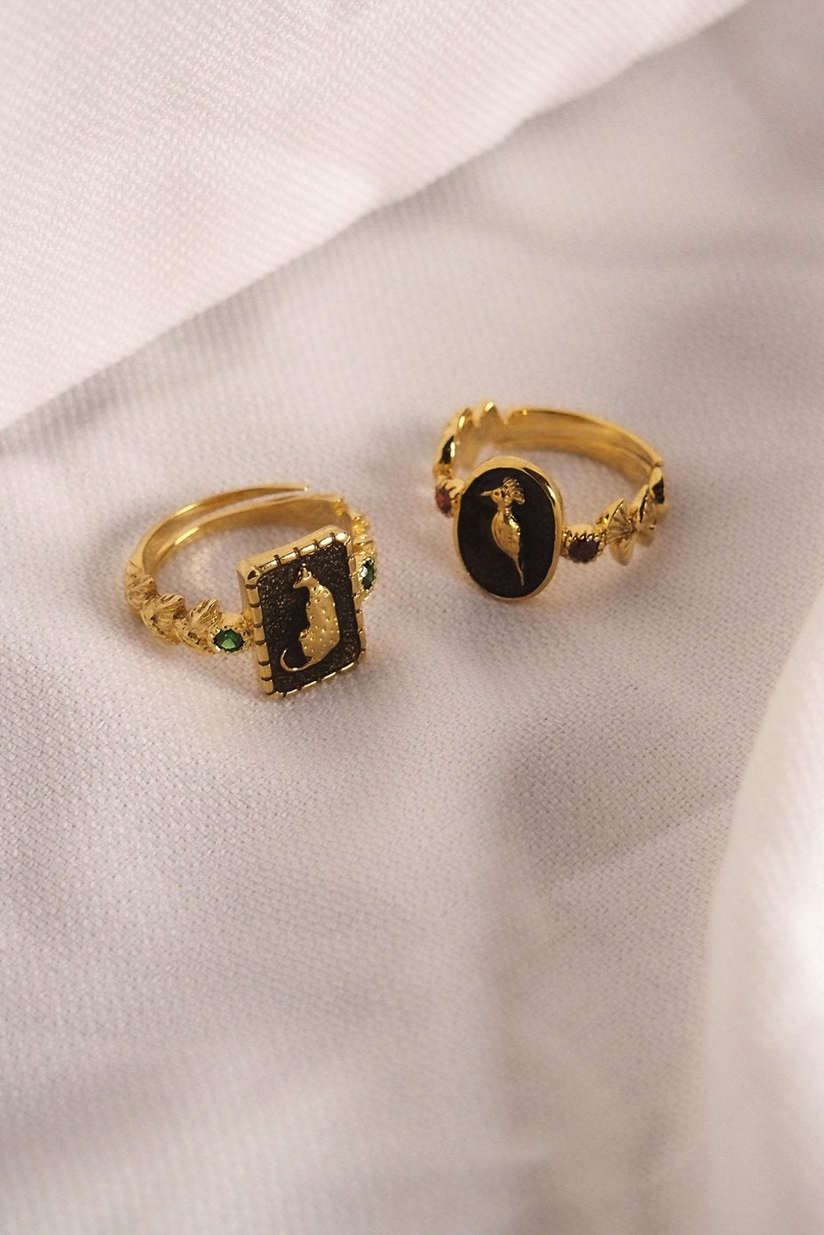 Unique collection of golden rings featuring animal motifs and decorative stones placed on a fabric.