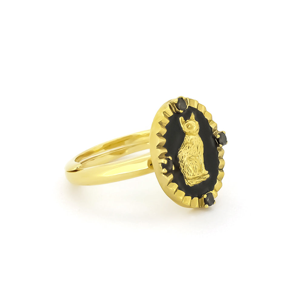 Gold ring featuring a cat design set in a black oval, surrounded by small black gemstones.