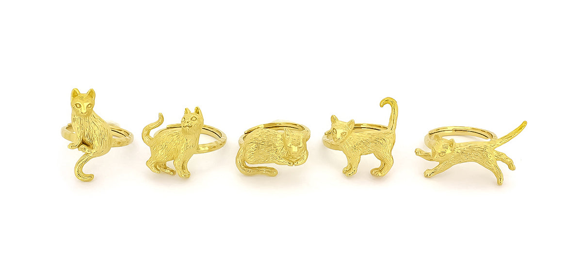 A collection of gold rings featuring playful cat designs in various poses, highlighting their detailed craftsmanship.