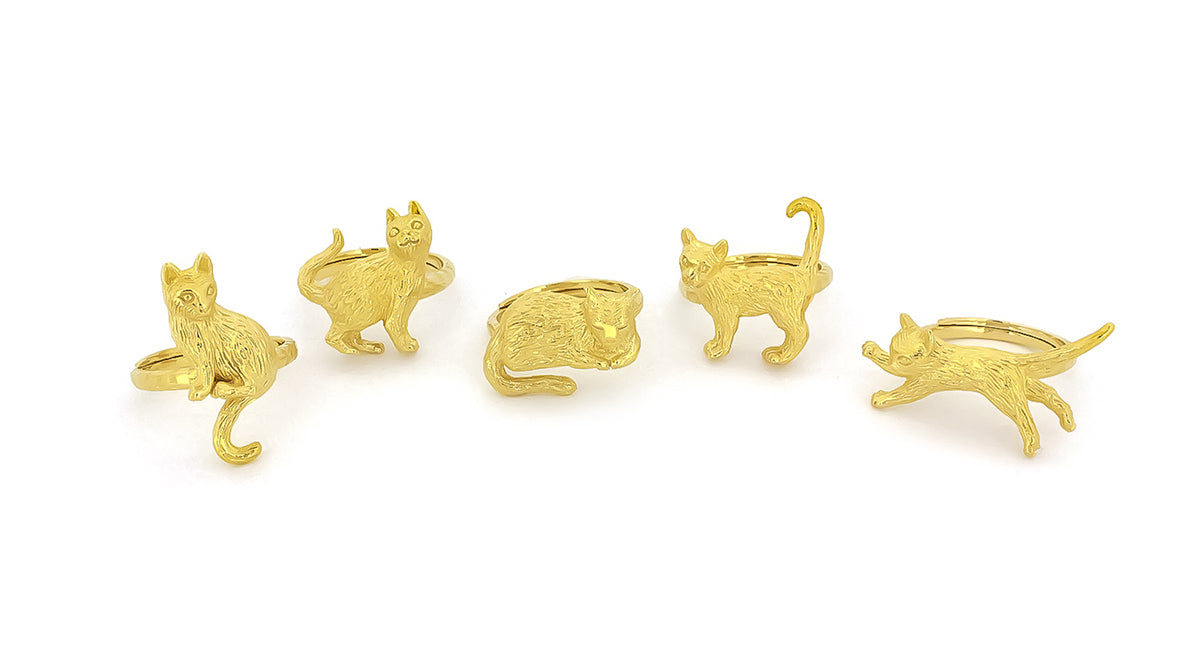 A collection of gold rings featuring playful cat designs in various poses, showcasing intricate detailing in its fur and features.