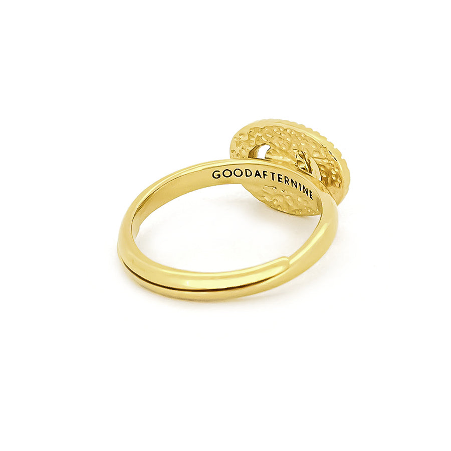 Gold ring with a central stone surrounded by textured rays, inspired by the moon.