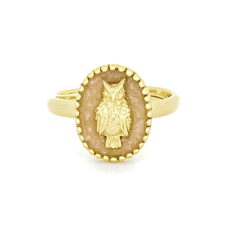 Gold ring featuring a carved owl design set in an oval background.